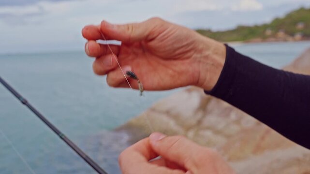 Close Up First Person View of Soft Fishing Lure on Hook Above Tropical Sea Near Rocky Shoreline, Saltwater Angling and Outdoor Recreation