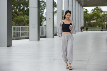 Fototapeta premium Woman walking and using smartphone in a spacious modern hall