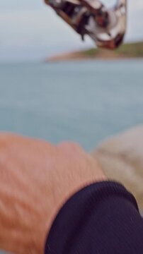 Vertical video. First Person View of Hands Holding Spinning Rod and Reel Above Tropical Rocky Coastline, Saltwater Fishing and Active Outdoor Lifestyle