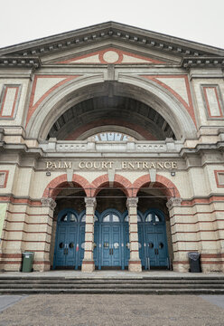 An eye-level view captures the stately, symmetrical facade of Alexandra Palace's Palm Court Entrance, historically known as "The Palace of the People" or "Ally Pally." The building's Victorian eleganc