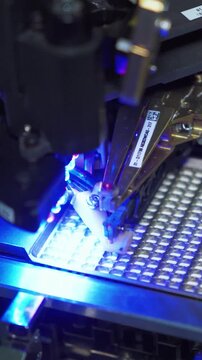 Robot chips placement. Robotic device deposits microchips onto dense LED grid under inspection. Vertical video. Automated robotic head places chips on densely packed LED array during quality check