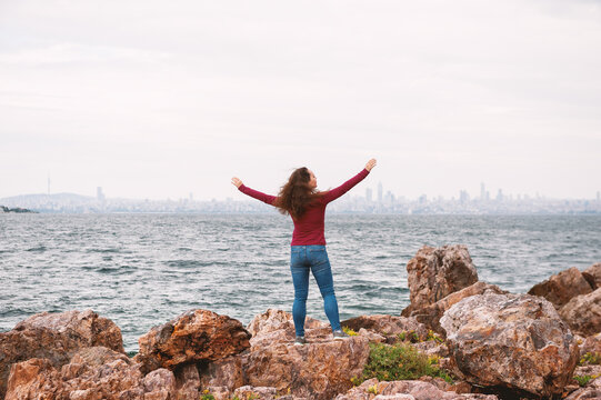 Traveler woman embracing coastal freedom near skyline