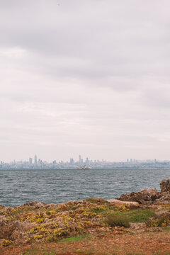 Rocky coastline facing distant skyline with ferry crossing water