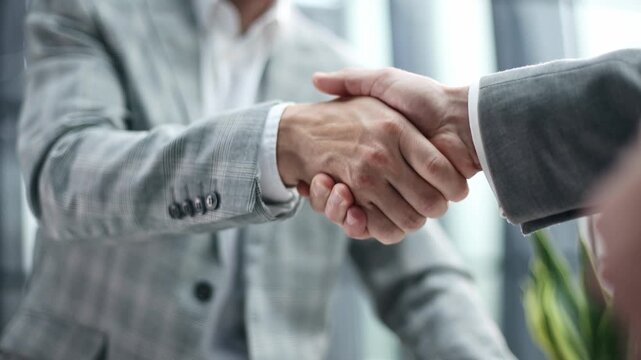 Two professionals shake hands firmly in a modern office