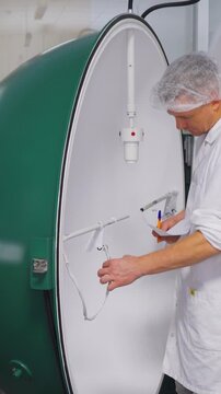 Laboratory scientist calibrates light spectrum. Vertical video. Researcher adjusts cables and inspects samples. Scientist in laboratory setting measures light spectrum and records data precisely