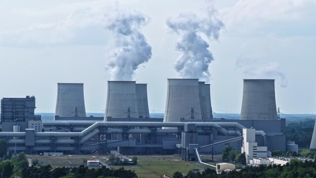This high-resolution aerial photograph captures a large thermal power plant with its characteristic hyperbolic cooling towers prominently featured. 