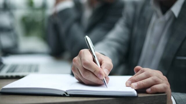 Hand writes notes in a notebook