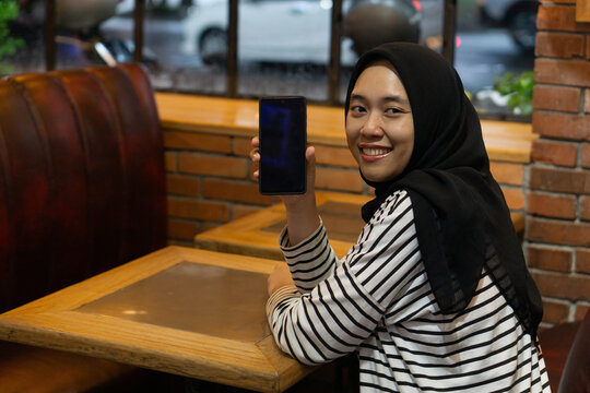 A young girl showing smartphone on a cafe with smilling