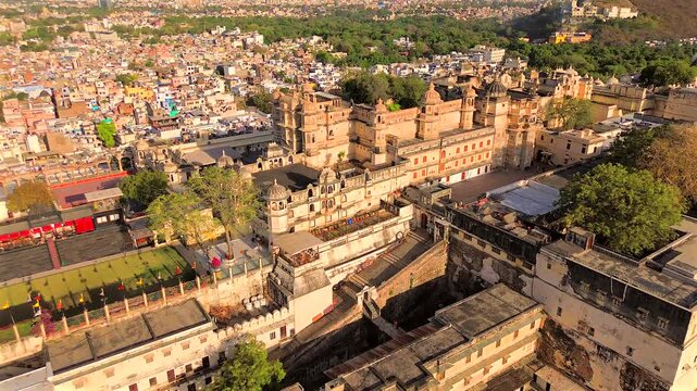 A high-angle wide static shot looking down at the intricate courtyards, terraces, and white stone architecture of the City Palace complex in Udaipur, Rajasthan, India