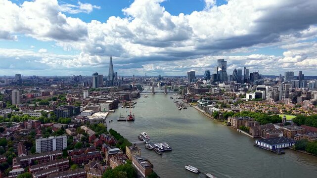 Establishing aerial view of the London cityscape along the River Thames during a summer day with sun and clouds