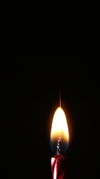 A bright candle on dark background ignites and burns with a tall steady flame, then is abruptly extinguished, leaving darkness, showing the full cycle of light and end.
