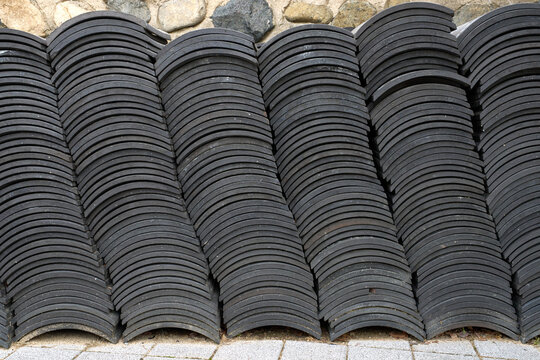 Abstract pattern of stacked traditional dark grey clay roof tiles on street, showcasing unique texture and rhythmic architectural design