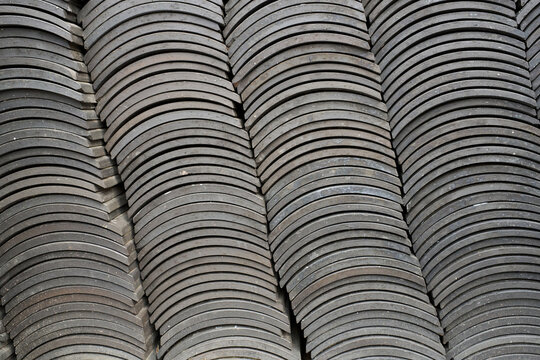 Abstract pattern of stacked traditional dark grey clay roof tiles, showcasing unique texture and rhythmic architectural design.