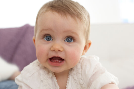 Portrait of baby girl with open mouth showing first teeth
