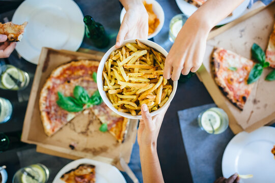 Hand taking French fries from bowl