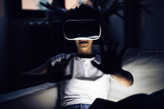 Young woman using VR goggles at home