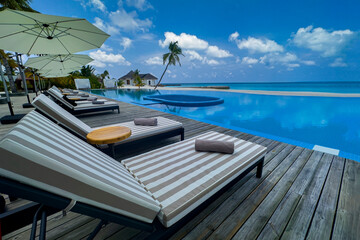 Fototapeta premium Summer vacation concept with poolside sun loungers at a luxury island resort with Bedchair near poolside in the tropical blue background