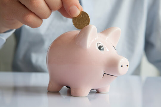 Man putting coin into piggy bank, close-up