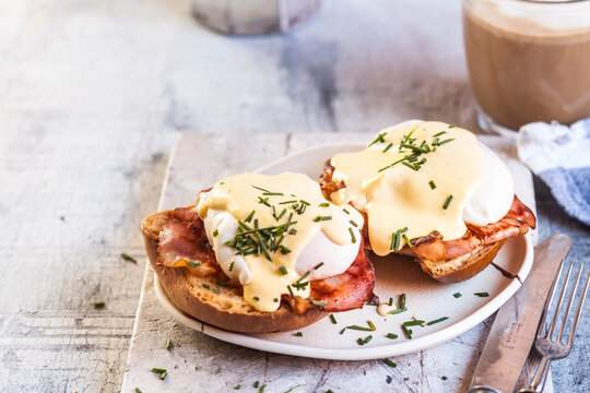 Traditional egg benedict with slices of bacon on toast, poached egg and hollandaise