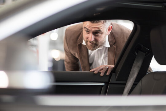 Man looking into car in car dealership