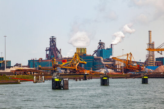 Industrial steel factory and port terminal with smoking chimneys and heavy machinery at tata steel ijmuiden in netherlands