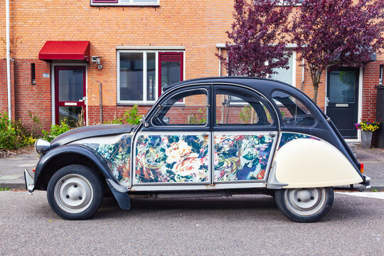 Amsterdam, Netherlands - 22.01.2026: Vintage citroen 2cv car with custom floral pattern doors parked on street in front of brick houses in netherlands