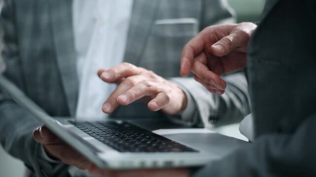 Two hands operate a laptop with focused intent