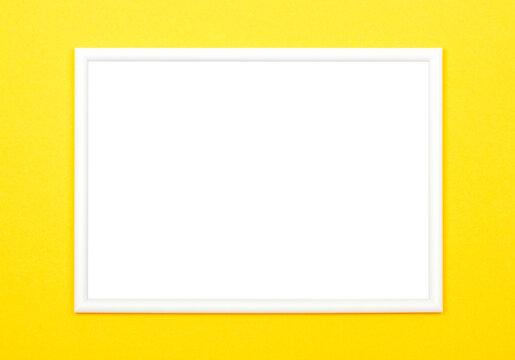 White picture frame on bright yellow background, flat lay.