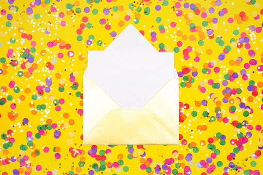 Open white envelope on yellow background with colorful confetti.