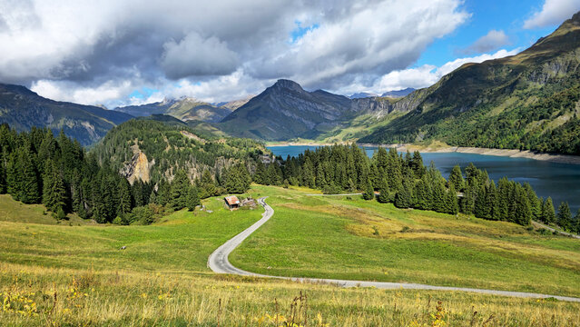 Alpine landscape showing Roselend Lake with road and mountains, Beaufort, Savoie, France, Europe.