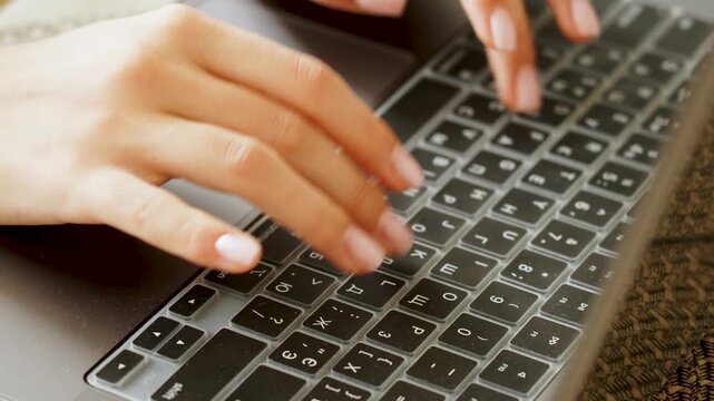 Hands typing on a modern laptop keyboard featuring English and Cyrillic letters