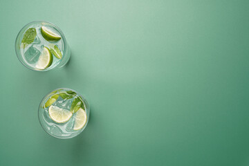 Two minimal mojito cocktails with copy space on pastel green background © hannamartysheva