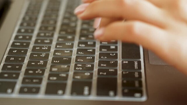 Hands typing on a silver laptop keyboard at a desk during daytime