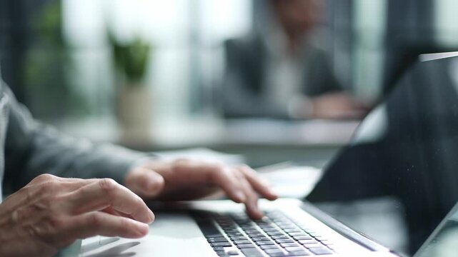 Hands type on laptop in modern office