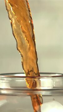 A super slow motion jet of black tea pours into the teapot. On a white background. Filmed on a high-speed camera at 1000 fps.