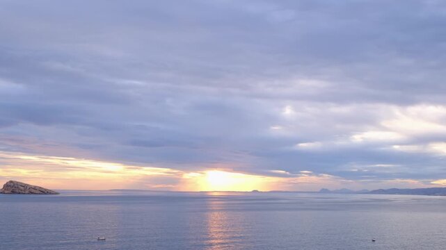 Sunset view over Cala Tio Ximo and Benidorm island. Tranquil winter sea, soft sunset glow, peaceful view of small island near Benidorm. Quiet natural beauty, no people, only sea and sky.