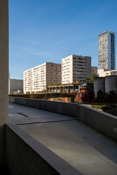 Concrete walkway leads toward residential housing and tower blocks in the urban cityscape of Paris, France, where architecture opens in clean light
