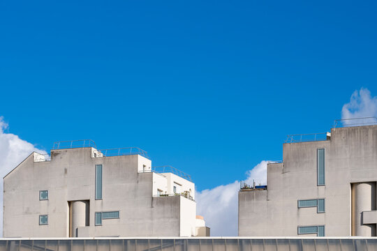 White rooftops and facade lines define urban housing architecture in Paris, France, where a clean sky and drifting clouds frame the stepped block