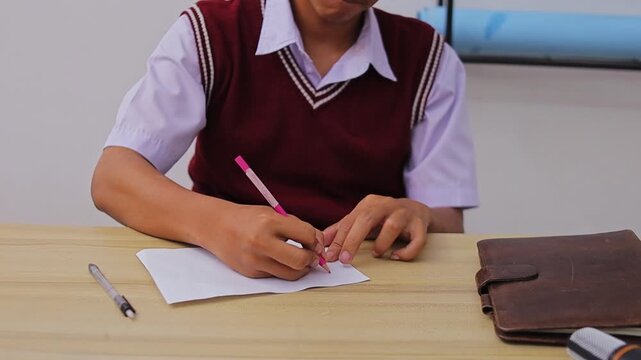 Close-up of student hands drawing notes on paper on table