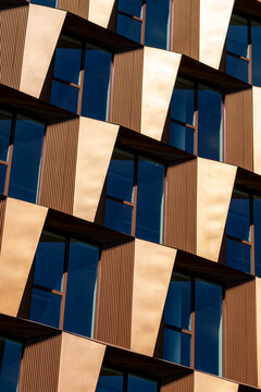 Warm panels and dark glass give a modern building facade an urban architecture rhythm of abstract geometry, pattern, shadow and detail
