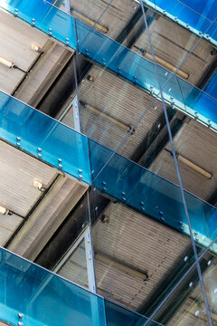 Blue glass cuts across a modern building facade, turning urban architecture into abstract geometry, layered pattern and precise structural detail