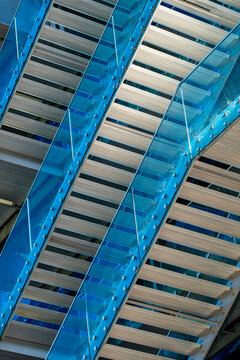 Blue glass escalator lines cross a modern building facade, where urban architecture shifts into abstract geometry, diagonal pattern and structural detail