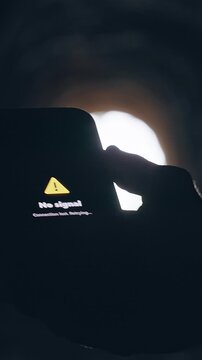 Vertical video. Smartphone Displaying No Signal Warning Inside Dark Tunnel, Cinematic Isolation Scene About Lost Communication and Technology Failure During Emergency