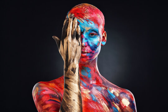 Paint, art and rainbow with portrait of woman in studio for self expression, glow and half face. Aesthetic, beauty and color splash with person on black background for abstract makeup and creative