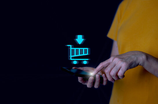 Person using smartphone with glowing online shopping cart hologram, symbolizing e-commerce, mobile shopping, digital payment, modern retail technology in a futuristic digital world.