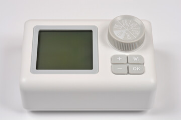Front angle view of a white digital garden water timer controller with an LCD screen and dial isolated on a white background. © nahhan