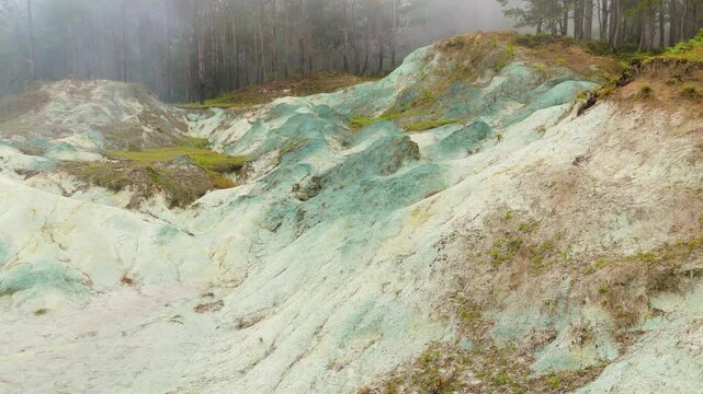 Aerial parallax reveals surreal Blue Soil Hills in Sagada Philippines, showing otherworldly white and blue-green mineral clay mounds rising from misty pine forest landscape