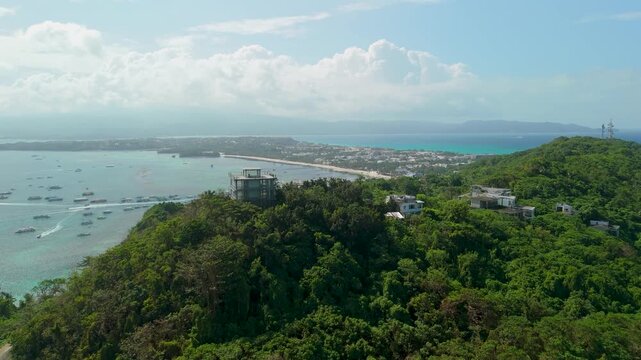 Aerial approach towards Mount Luho View Deck observation tower in Boracay reveals panoramic view of Bulabog Beach bay, turquoise water and dozens of moored boats