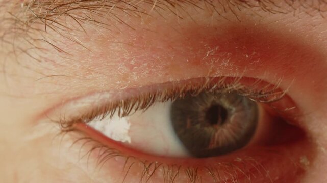 Stunning macro of a man's blue eye looking at something off screen and depicting several emotions