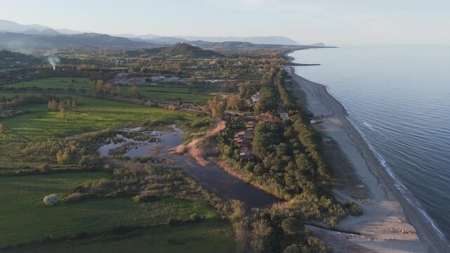 Aerial coastline view of Spiaggia di Perd'e Pera in Sardinia with long beach and green land, drone